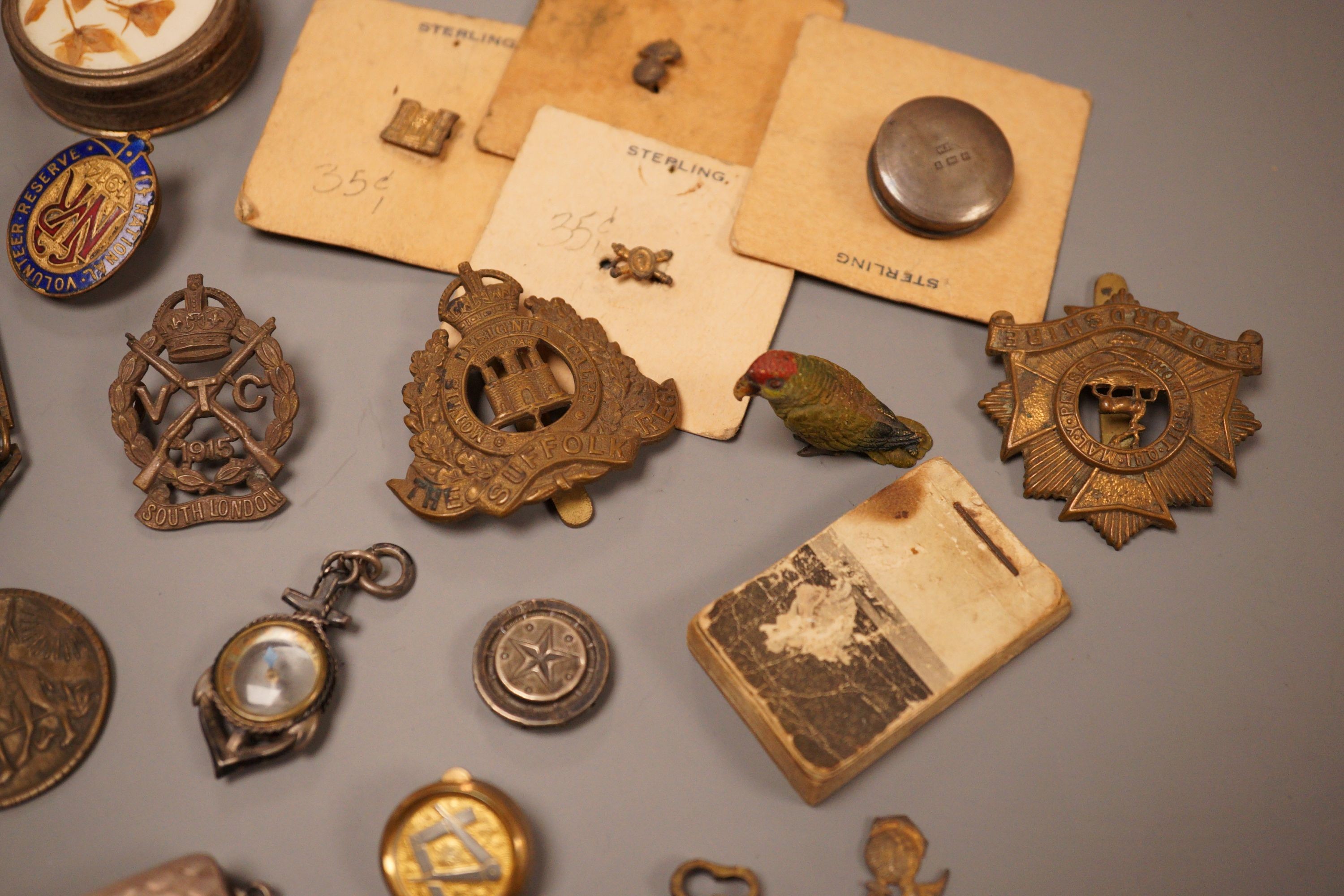 A selection of various miscellaneous items, to include a George III silver vinaigrette, a military pin badge, an Edwardian flick book, a cold painted parrot, and others.